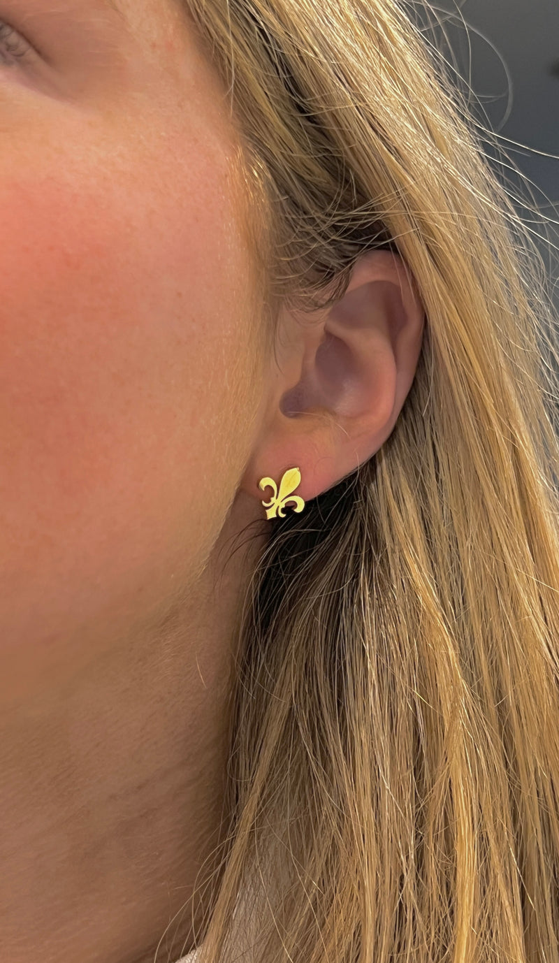 Fleur de lis stud earrings worn on ear, side view